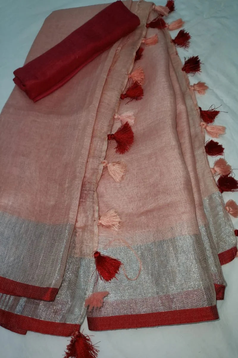 Peach linen saree with silver-zari and red border draped elegantly