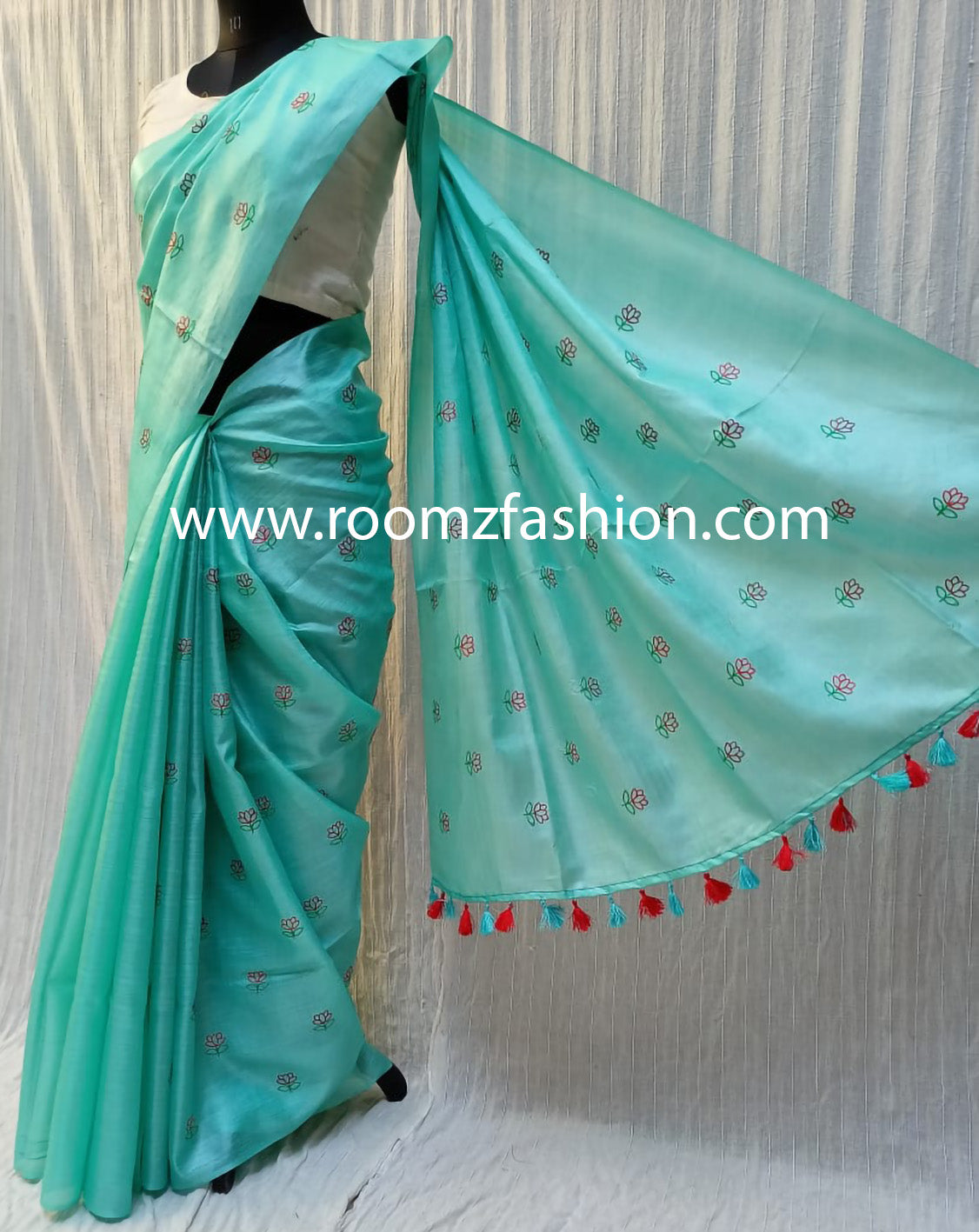 Hand-stitched floral embroidery detail on green saree