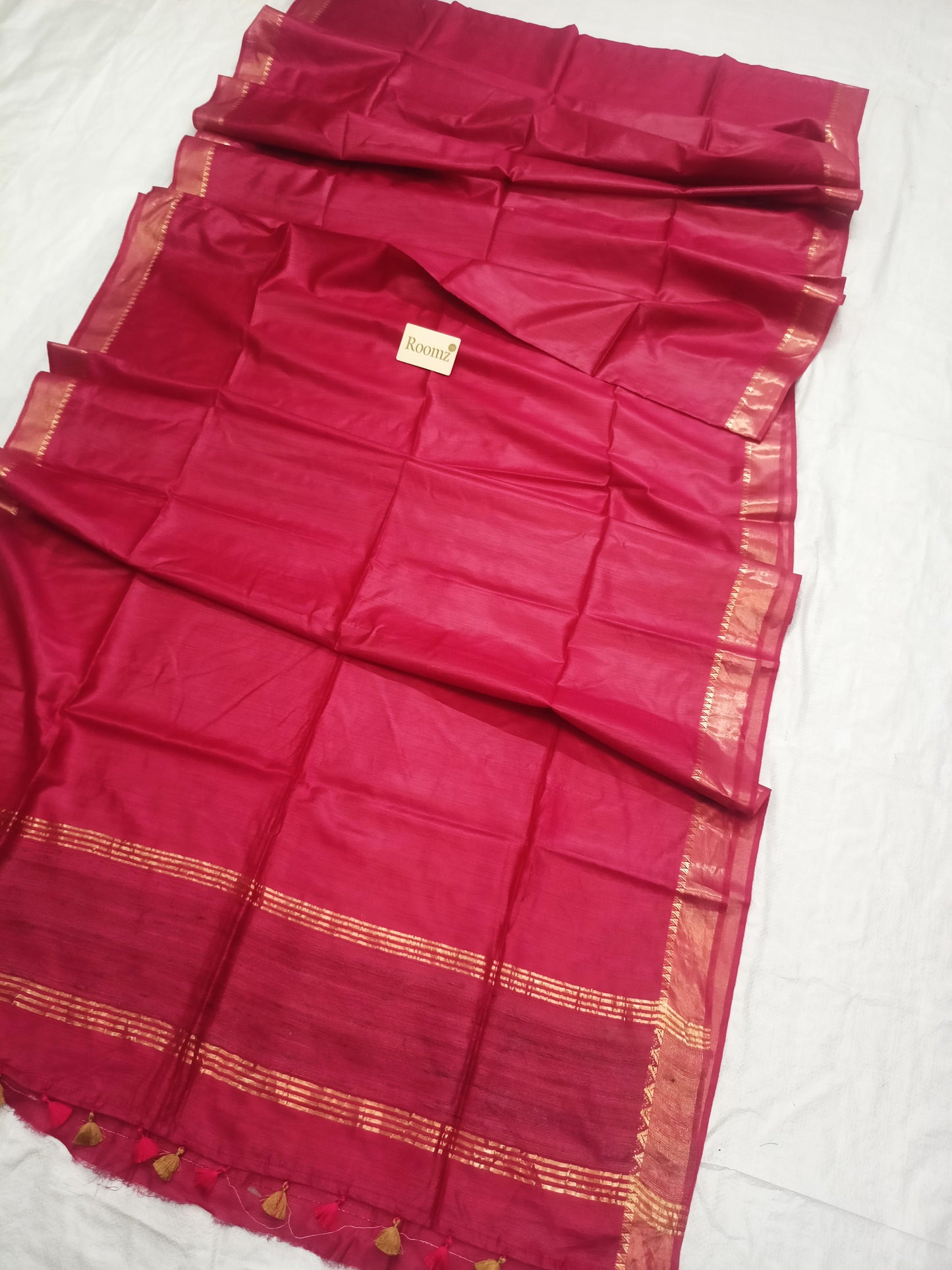 Close-up of the golden zari border on the red silk saree


