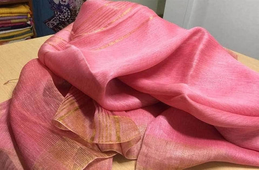 Pink silk linen saree with golden zari border draped elegantly

