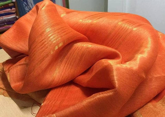 Vibrant orange silk linen saree with golden zari border draped elegantly